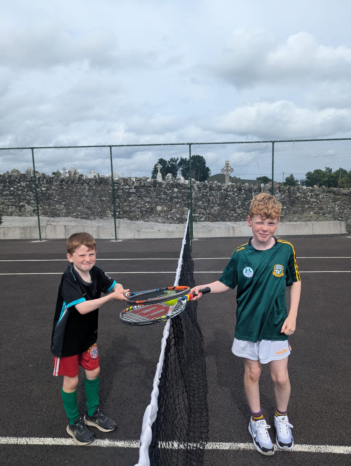 Two young players shaking racquets over the net