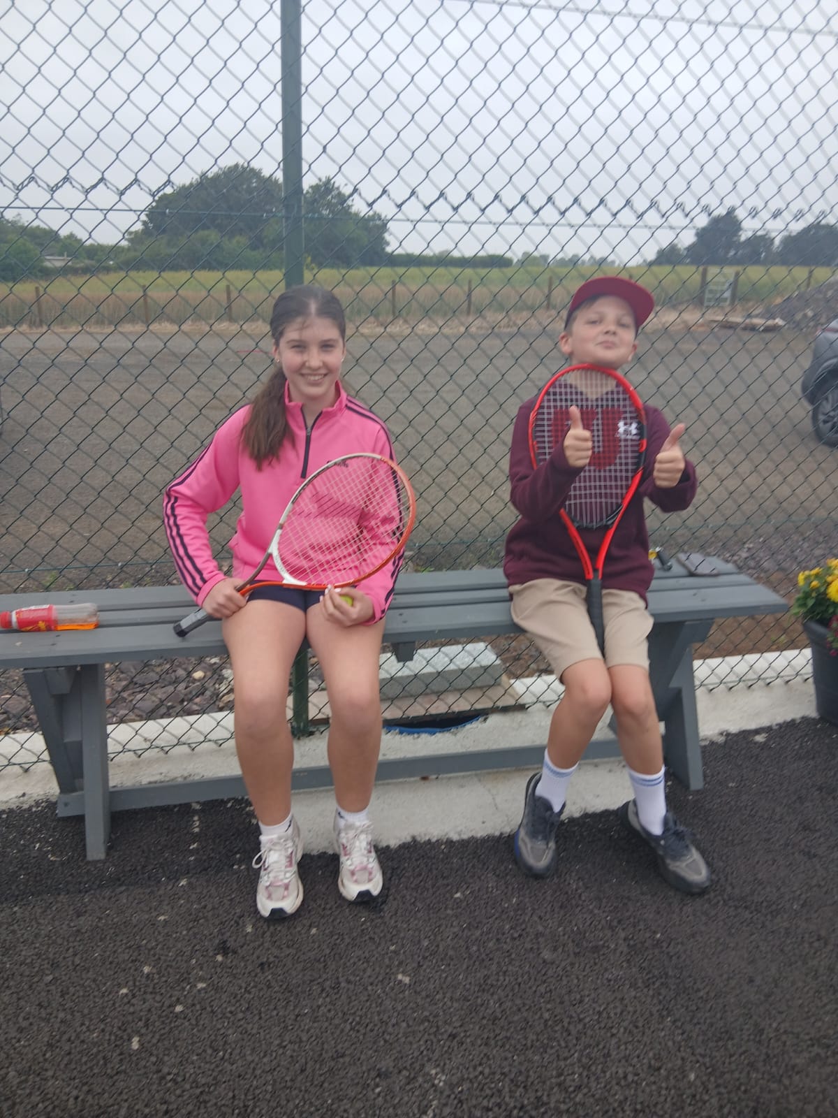 Two juniors giving a thumbs up on the bench
